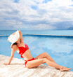 © New Africa - Beautiful woman sitting on edge of swimming pool with infinity view on ocean