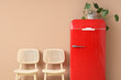 © Pixel-Shot - Chairs and red fridge near beige wall in interior of room, closeup