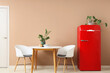 © Pixel-Shot - Chairs, table and red fridge near beige wall in interior of kitchen