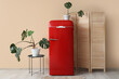 © Pixel-Shot - Folding screen, table, red fridge and houseplants near beige wall in interior of room
