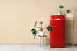 © Pixel-Shot - Folding screen, table, red fridge and houseplants near beige wall in interior of room