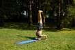 © Cavan - Practicing yoga headstand in a peaceful green park setting
