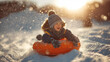 © imagemir - A joyful Caucasian boy with a playful smile sledding on a snowy hill, surrounded by sparkling snowflakes at sunset.