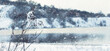 © Larysa - Snowfall on a frosty winter day over snow-covered hills and a frozen river or lake, with dry grass in the foreground, creating a melancholy and peaceful natural landscape