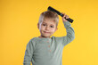 © New Africa - Little boy brushing his hair on orange background