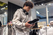 © Светлана Мищенко - Teen boy shopping for shoes in clothing store — young man holding black boots, teenage fashion, footwear shopping, modern retail, youth lifestyle, generation Z consumer