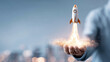 © kaliel - A hand launching a small rocket, representing startup growth product launch momentum and the ignition of innovative ideas into the market.