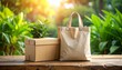 © andre - Eco-friendly shopping bag and cardboard box with green plants on a wooden table in sunlight