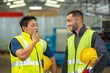 © BESTIMAGE - Two men wearing yellow vests and hard hats are talking in a factory.
