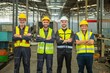 © BESTIMAGE - A group of four factory workers wearing hard hats and safety vests are posing for a photo in the factory.