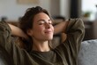 © VolumeThings - Content brunette woman relaxes on a sofa in a modern living room eyes closed and hands behind her head enjoying solitude and dreaming with a smile