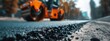 © Valentina - Road repair: close-up of fresh asphalt and road roller at a dynamic low angle
