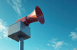 © miss irine - Red siren on pole against blue sky. It is used to provide emergency alert and warning during crisis like weather hazard disaster. Alarm system sends signal. Sound equipment provides public safety.