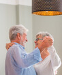 © Daniel - Joyful active old retired romantic couple dancing laughing in living room, happy middle aged wife and elder husband having fun at home, smiling senior family grandparents relaxing bonding together