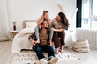 © BullRun - Girl giggling on dad’s shoulders while mother supports both, heartwarming family moment full of joy, playful energy, and strong emotional closeness in peaceful home space.