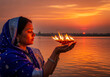 © ArtFocus Studio - Woman holds oil lamps at sundown near the water. A tranquil profile filled with faith. Spiritual practice, religious observance, hindu culture.