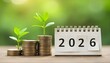 © Rama - Young green plants sprouting from stacks of coins beside a 2026 calendar, symbolizing growth, savings, and financial planning for the new year