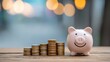 © SOEM - A pink piggy bank with a smiling face, standing on a wooden table with a stack of coins in front of it.