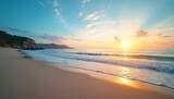 Golden sun sets over calm ocean beach with soft light. Gentle waves roll onto vast sand shore. Coastal mountains, green hills meet blue sea. Sky soft clouds. Tropical nature scene peaceful, great for
