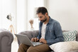 © fizkes - Focused businessman freelancer using notebook on sofa in living room