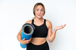 © luismolinero - Young caucasian woman going to yoga classes while holding a mat isolated on white background having doubts while raising hands