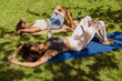 © Drobot Dean - Two female athletes lie on mats with rubber bands on their thighs and talk