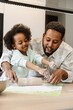 © Drobot Dean - A daughter sprinkles flour on the dough her father is rolling out as they stand at the table and talk