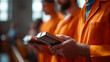 © Kateryna - Inmates' hands holding Bibles in prison chapel orange jumpsuits visible faces not shown correctional mental health faith rehabilitation prison worship service with copy space
