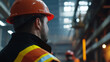 © A2Z AI  - A construction worker in safety gear. Wearing a hard hat and reflective vest, he stands in a factory. His gaze is fixed forward, focused on the ongoing work in the industrial area.