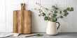 © Basir  - Rustic wooden cutting board and eucalyptus branches in a white pitcher on a countertop