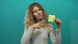 © Krakenimages.com - Woman uses her hand for pointing in a studio space, presenting blonde young pose with note showing yellow tax reminder against a teal backdrop.