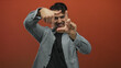 © Krakenimages.com - Young hispanic man making frame gestures with hands on an isolated red background, expressing creativity and focus in a filmmaking or photography context.