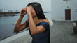 © Krakenimages.com - Woman making binocular gesture on seaside promenade, showcasing latin and hispanic flair with sea in background, blending outdoor playfulness and leisure.