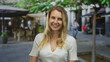 © Krakenimages.com - Woman smiling on urban street with blonde hair wearing white shirt outdoors in city setting showing casual happiness in lively environment under sunny sky with blurred background.