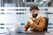 © Liubomir - Young focused businessman working with a laptop at his desk in a blurred modern office environment, representing concentration, dedication, and professional productivity