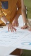 © rogerphoto - Business professionals analyzing financial reports, pointing at data points on charts and graphs lying across white desk surface