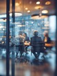 © Johannes - blurred background of a business meeting in a modern office with people sitting at a table a team working together having a discussion view through a glass wall