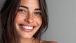 © Johannes - close up face of young woman with beautiful smile isolated on grey wall with copy space successful multiethnic girl latin woman looking at camera against gray wall with a big whitening teeth smile no