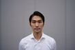 © Praant - Portrait of a man with dark hair and a white shirt against a gray background looking at camera