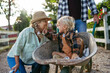 © Halfpoint - Grandmother playing with grandson in a wheelbarrow on a family farm.