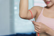 © amnaj - Woman measuring her bicep with a red tape measure, tracking progress in her health and fitness journey