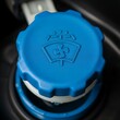 © Ndx - A close-up showcases a bright blue cap featuring a washer fluid symbol with the nozzle, sprays, and wiper detail