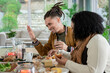 © Wavebreak Media - Mid adult couple sitting at wooden dining table at home, holding glass and cutting bread