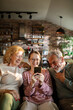 © Geber86 - Granddaughter with grandparents using smartphone at home