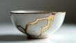 © Vadym - Close up of white ceramic bowl with golden cracks on surface. Traditional Japanese kintsugi style pottery repaired with gold lines. Art and design. Concept of value of imperfection.