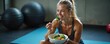 © Vadym - Fit woman eats healthy salad after gym workout. Female athlete rests on yoga mat enjoying fresh vegetables. Nutrition for strong body and mind.