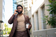 © Dexon Dee - Black businessman talking on phone, drinking coffee outdoors