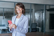 © Stock 4 You - Portrait of mature businesswoman CEO holding smartphone using fintech app looking at camera in office. Smiling Latin Hispanic adult professional business woman using mobile phone cellphone. Copy space