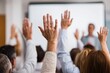© oksa_studio - People raising hands in an audience during a conference, actively participating by asking questions or voting