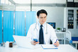 © laddawan - Asian Doctor using tablet to review medical results. Diverse healthcare professionals in modern hospital clinic